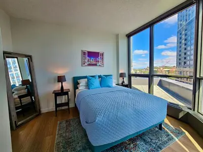 a bedroom with a blue bed and a large window at Calgary&Downtown&BMO Centre & Parking in Calgary