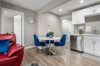 a kitchen and dining room with a table and blue chairs at Cozy & Large Furnished 2-Bedroom Suite in Calgary