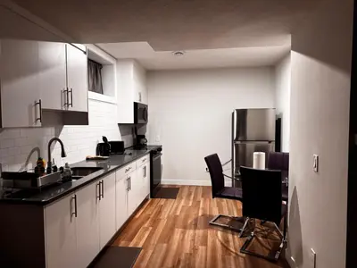 a kitchen with black counter tops and a refrigerator at Homey Basement Suite by Gaudi in Calgary