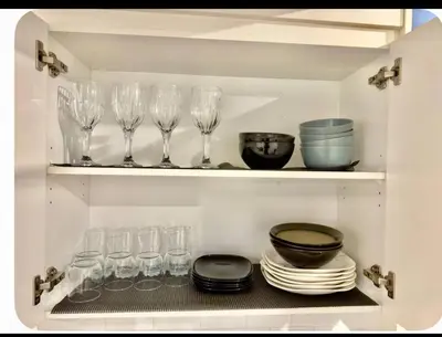 a cupboard with wine glasses and plates and bowls at Homey Basement Suite by Gaudi in Calgary