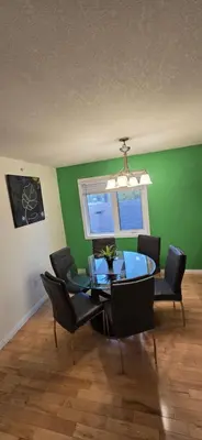 a dining room with a glass table and chairs at Northern Manor in Yellowknife