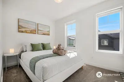 a white bedroom with a bed with a teddy bear on it at Modern Luxury Townhome near Aspen Landing and Winsport in Calgary