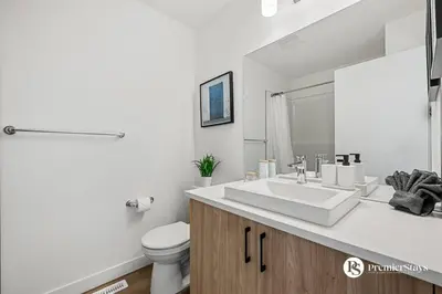 a white bathroom with a sink and a toilet at Modern Luxury Townhome near Aspen Landing and Winsport in Calgary