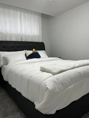 a large white bed with white sheets and pillows at One bedroom private entrance suite in Edmonton