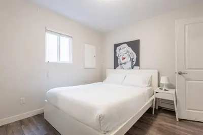 a white bedroom with a white bed and a picture of a dog at Sleek Modern Escape Suite - Comfort and Style in the City in Vancouver