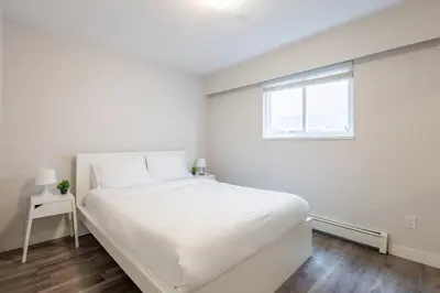 a white bedroom with a bed and a window at Sleek Modern Escape Suite - Comfort and Style in the City in Vancouver