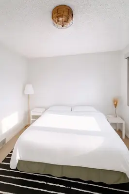 a white bedroom with a white bed and a rug at Great Northern Escapes - The Managers House in Yellowknife