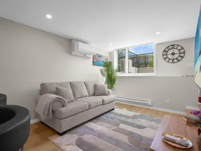 a living room with a couch and a clock on the wall at Exquisite 1-Bdr Condo Apt in Calgary