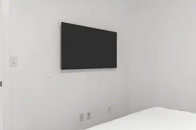 a flat screen tv hanging on a white wall at Newly Built 2BR and 2BA MtnView Retreat in DT Canmore in Canmore