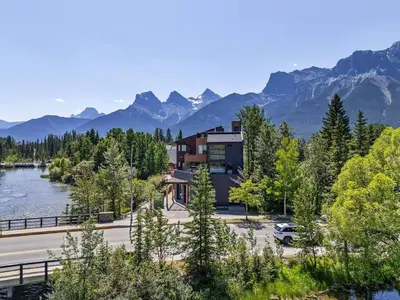 a house on the side of a river with mountains at Newly Built 2BR and 2BA MtnView Retreat in DT Canmore in Canmore