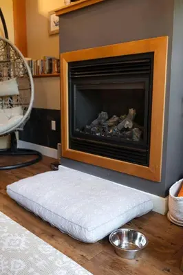 a white dog bed in front of a fireplace at The Inlet Haven - 2 Bedroom on the Inlet in Ucluelet