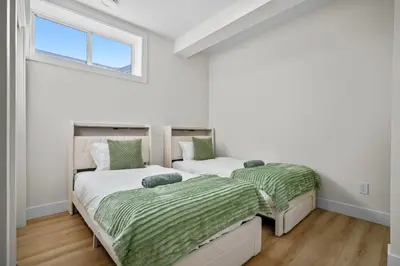 two beds in a room with white walls and a window at Private Sherwood Suite by Park in Calgary