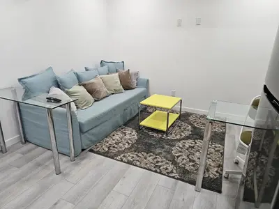 a living room with a blue couch and a glass table at Non Smoking- Stylish Basement Suite Near Airport, Trails & Dining in Edmonton