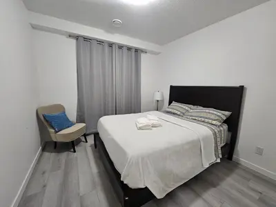 a bedroom with a large bed and a chair at Non Smoking- Stylish Basement Suite Near Airport, Trails & Dining in Edmonton