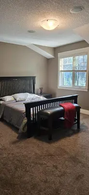 a bedroom with a bed with a bench and a window at Rocky View Bed & Breakfast in Calgary