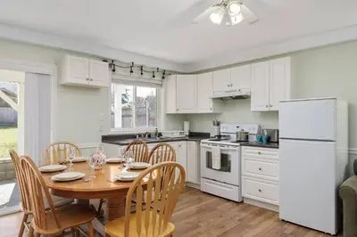 a kitchen with a wooden table and a white refrigerator at Cozy and Relaxing Private Getaway Free Parking in Nanaimo