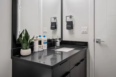 a bathroom with a sink and a mirror at NEW Restful Retreat with Hot Tub, King Bed, AC, Garage, Near WEM in Edmonton