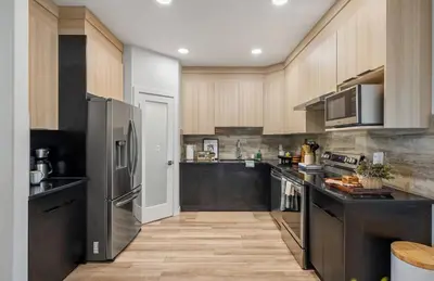 a large kitchen with black appliances and wooden cabinets at NEW Restful Retreat with Hot Tub, King Bed, AC, Garage, Near WEM in Edmonton