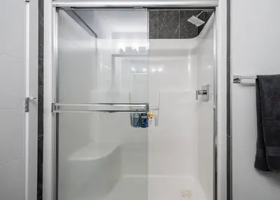 a shower with a glass door in a bathroom at NEW Restful Retreat with Hot Tub, King Bed, AC, Garage, Near WEM in Edmonton