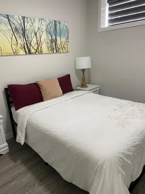 a bedroom with a bed with white sheets and red pillows at The Willow Nest lower suite-2 Rooms in Calgary