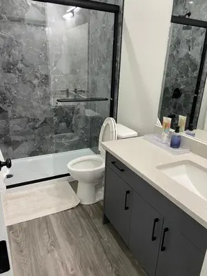 a bathroom with a shower and a toilet and a sink at The Willow Nest lower suite-2 Rooms in Calgary