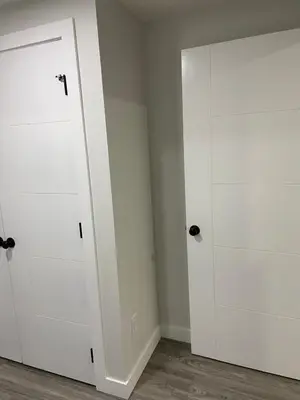 two white closet doors in a room with wood floors at The Willow Nest lower suite-2 Rooms in Calgary
