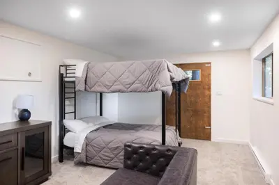 a bedroom with two bunk beds and a chair at Ocean Vista In the Woods on Saltspring Island in Salt Spring Island