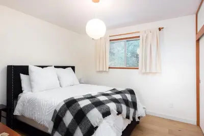 a bedroom with a black and white bed and a window at Ocean Vista In the Woods on Saltspring Island in Salt Spring Island