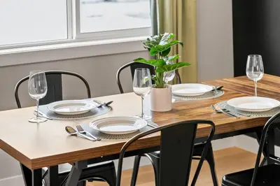 a wooden table with plates and wine glasses on it at Cowboy Chalet SE|AC|Games|King Bed|20 min to DT in Calgary