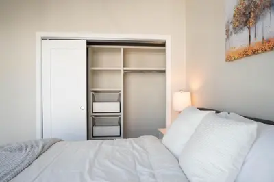 a bedroom with a white bed and a closet at City Views Walk to Calgary Tower and Stampede in Calgary