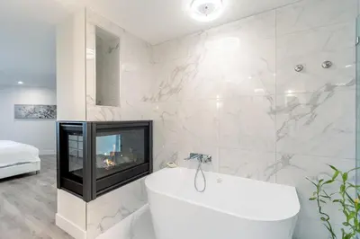 a bathroom with a fireplace and a white tub at High Tide Suite - New Bright Oceanfront Escape with Spa-like Bath in Nanoose Bay