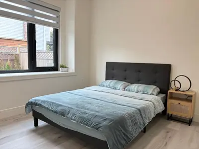 a bedroom with a bed with a blue blanket and a window at South surrey Secondary Suite with Kitchen in Surrey
