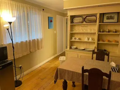 a dining room with a table and a shelf with dishes at Suit near Grousmountain in North Vancouver