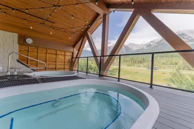 a hot tub in a room with a view of mountains at Rooftop Hot Tubs 2Bd 2Ba Corner Unit w Views in Canmore