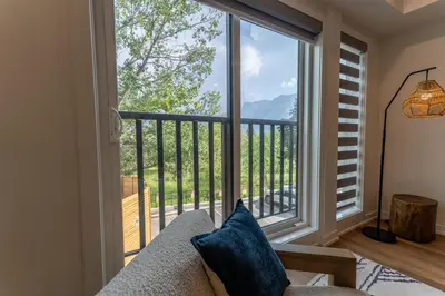 a living room with a large window with a view at Rooftop Hot Tubs 2Bd 2Ba Corner Unit w Views in Canmore