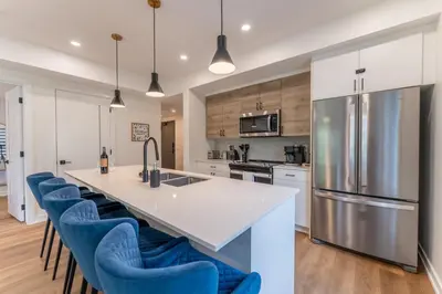 a kitchen with a large island with blue bar stools at Rooftop Hot Tubs 2Bd 2Ba Corner Unit w Views in Canmore