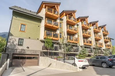 a large apartment building with cars parked in a parking lot at Rooftop Hot Tubs 2Bd 2Ba Corner Unit w Views in Canmore