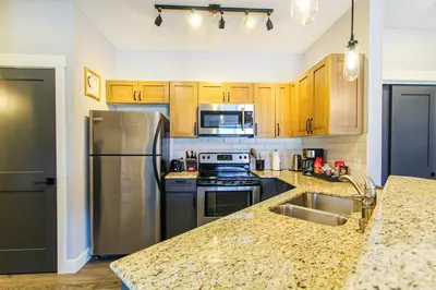 a kitchen with stainless steel appliances and wooden cabinets at Cozy King Condo Mountain Views, Resort Perk and BBQ in Canmore