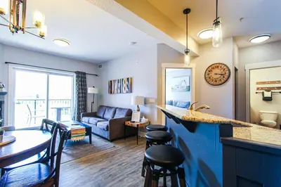 a kitchen and living room with a couch and a table at Cozy King Condo Mountain Views, Resort Perk and BBQ in Canmore