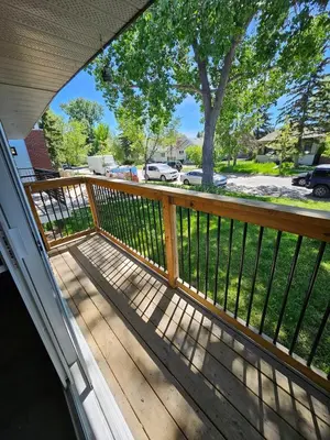 a porch with a wooden railing and a tree at The Onyx Suite In Inglewood Minutes To DT in Calgary