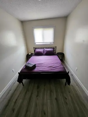 a bedroom with a bed with purple sheets and a window at The Onyx Suite In Inglewood Minutes To DT in Calgary