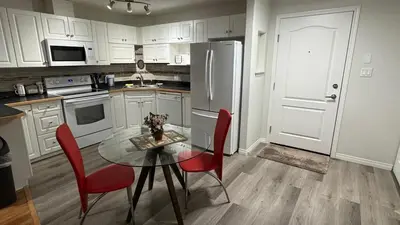 a kitchen with a glass table and red chairs at Main Floor Condo Fully Independent 1 Bed 1 Bath in Edmonton