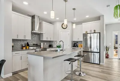 a kitchen with white cabinets and a kitchen island with bar stools at Cozy 3-Bedroom Family Retreat Home in Rangeview in Calgary