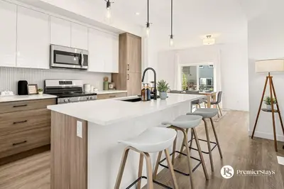 a kitchen with white cabinets and bar stools at Luxurious Designer Finished Home in Calgary
