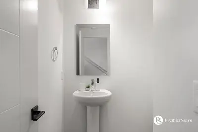 a white bathroom with a sink and a mirror at Luxurious Designer Finished Home in Calgary