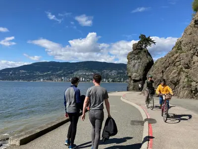 people walking and riding bikes on a path by the water at Cozy Condo in the heart of the city in Vancouver