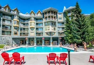 a large apartment building with a pool and red chairs at Cascade Lodge Studio-steps from village in Whistler