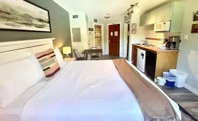 a large bed in a room with a kitchen at Cascade Lodge Studio-steps from village in Whistler