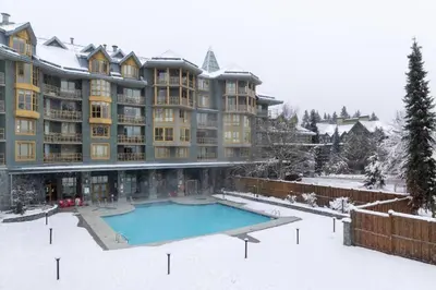 a large apartment building with a swimming pool in the snow at Cascade Lodge Studio-steps from village in Whistler