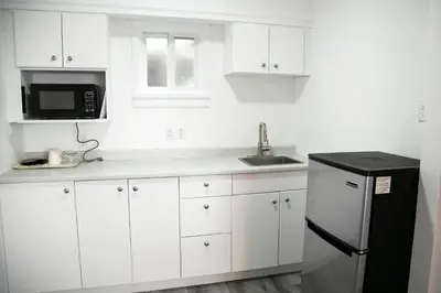 a kitchen with white cabinets and a black refrigerator at Westview Centre Motel Ltd in Powell River